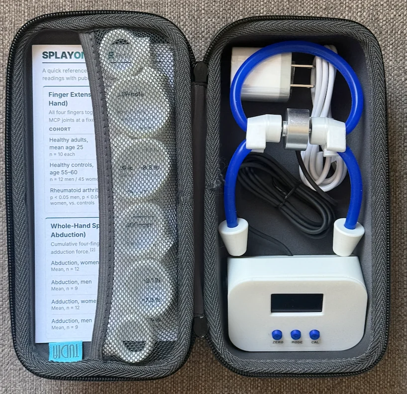Splayometer Clinical Kit packed in its zippered carrying case: measurement unit, hand loop, finger rings, USB-C charger and cable, and clinical reference card
